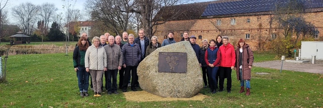 der Vorstand der Teilnehmergemeinschaft steht bei der Abschlussveranstaltung des Verfahrens um den neu eingeweihten Gedenkstein