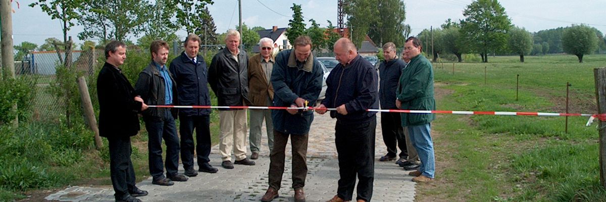zwei Personen zerschneiden ein rot-weißes Band zur Einweihung eines neuen Weges, 8 Personen sehen zu